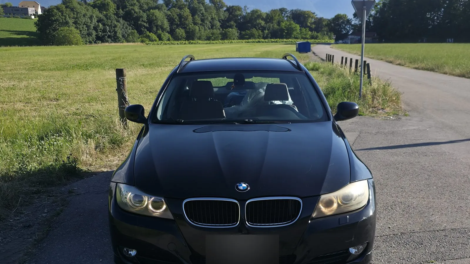 Break BMW Série 3 noir sur une route de campagne, Alpes vaudoises en arrière-plan