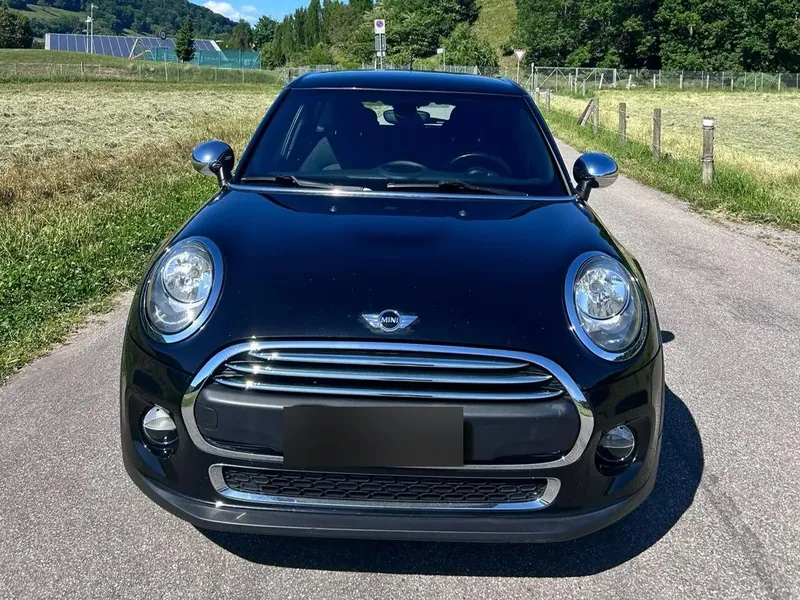 Mini Cooper noire sur une route de campagne, par grand soleil